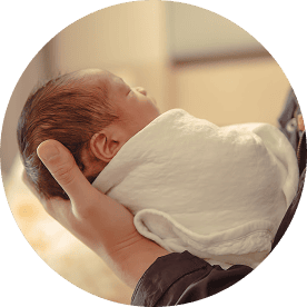 A newborn baby peacefully sleeping in a caregiver’s hand.