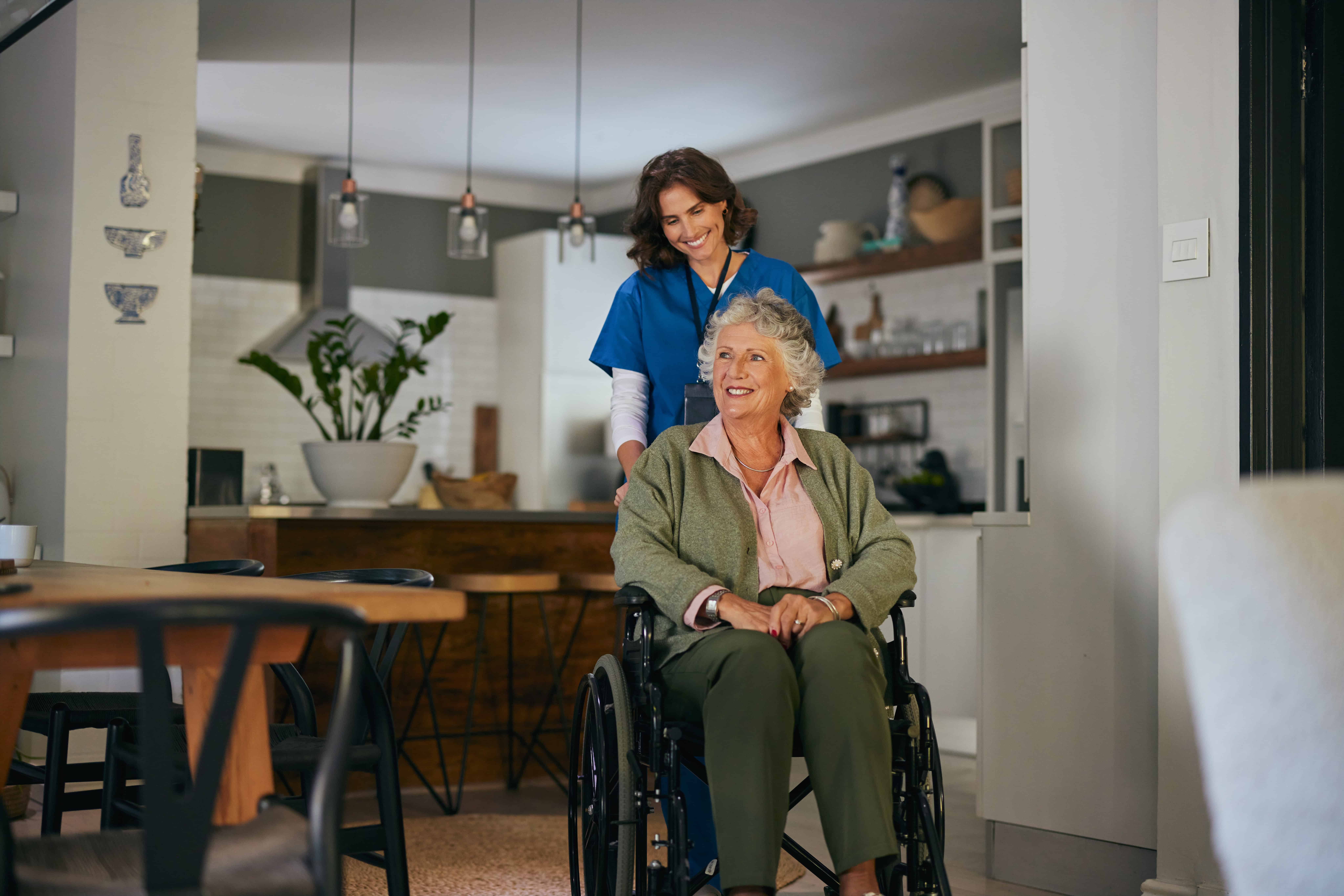 Caring healthcare professional assisting elderly woman in wheelchair at home.