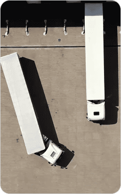 Two white delivery trucks parked side by side on a concrete lot.