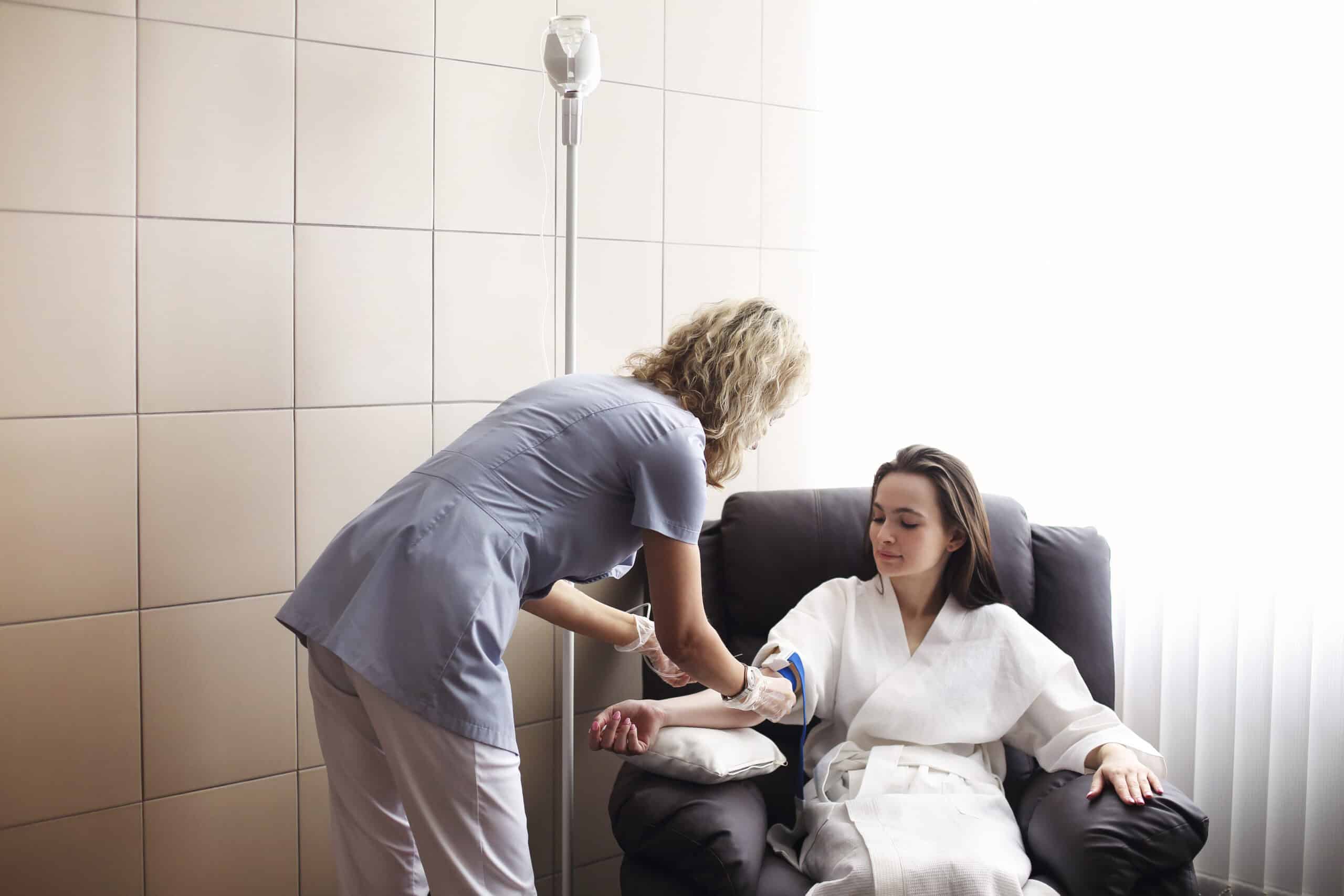 Nurse administering IV therapy to patient in hospital room.